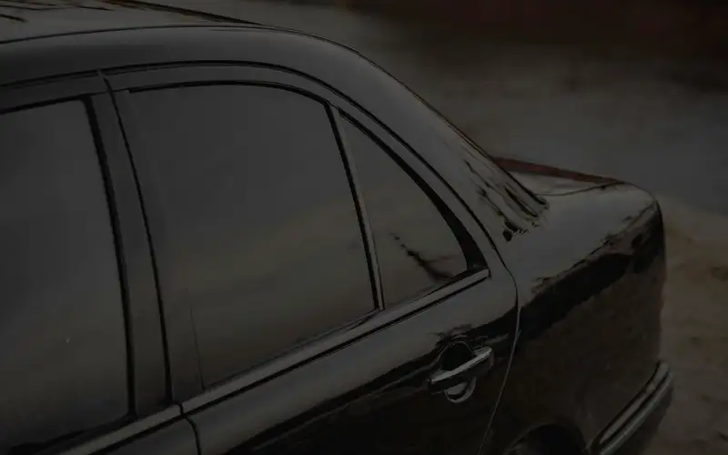 Dark tinted side windows on a black sedan