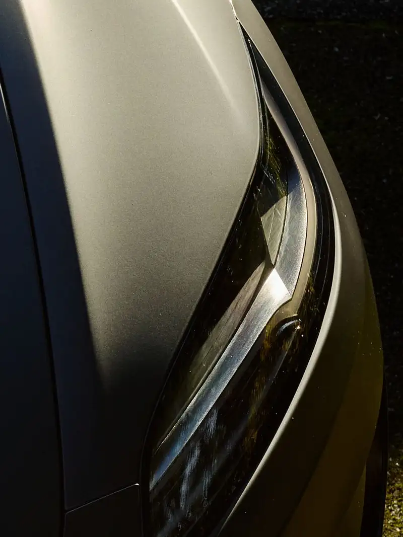 Matte grey car hood and headlamp catching low evening sun