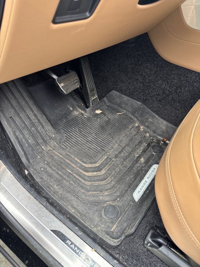 Before: dusty, debris-filled driver footwell and floor mat in a Range Rover