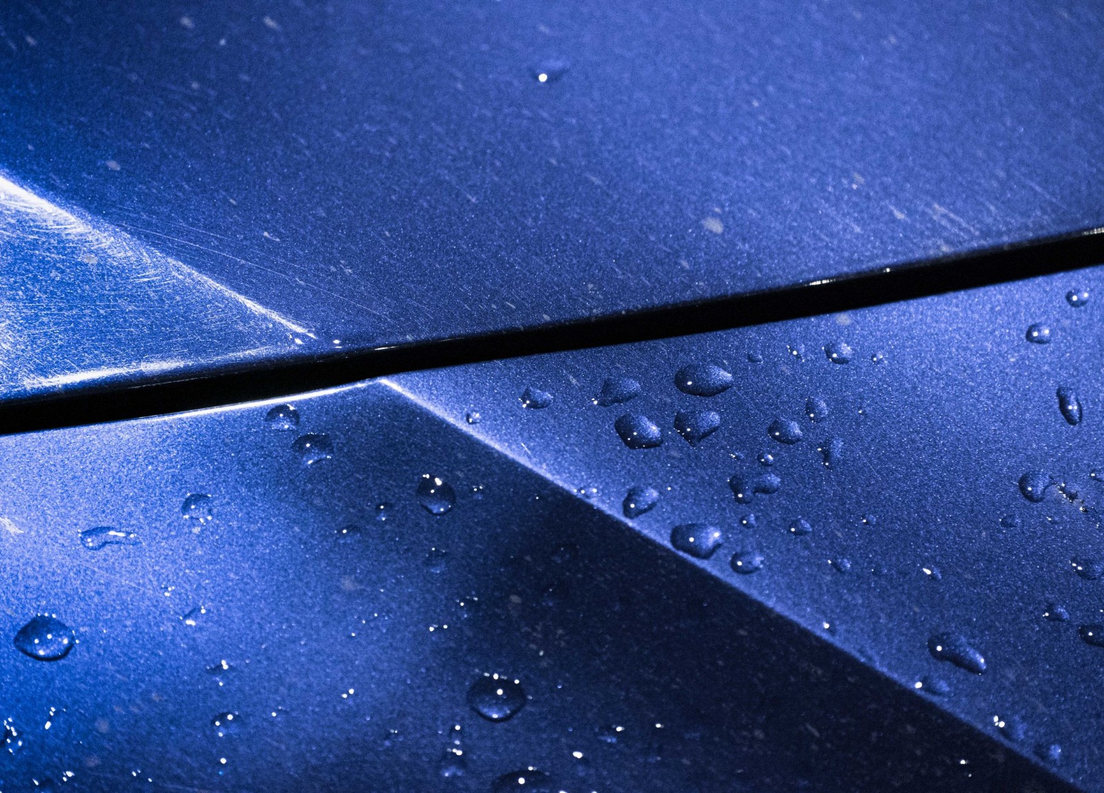 Water beading on a ceramic-coated deep blue vehicle panel