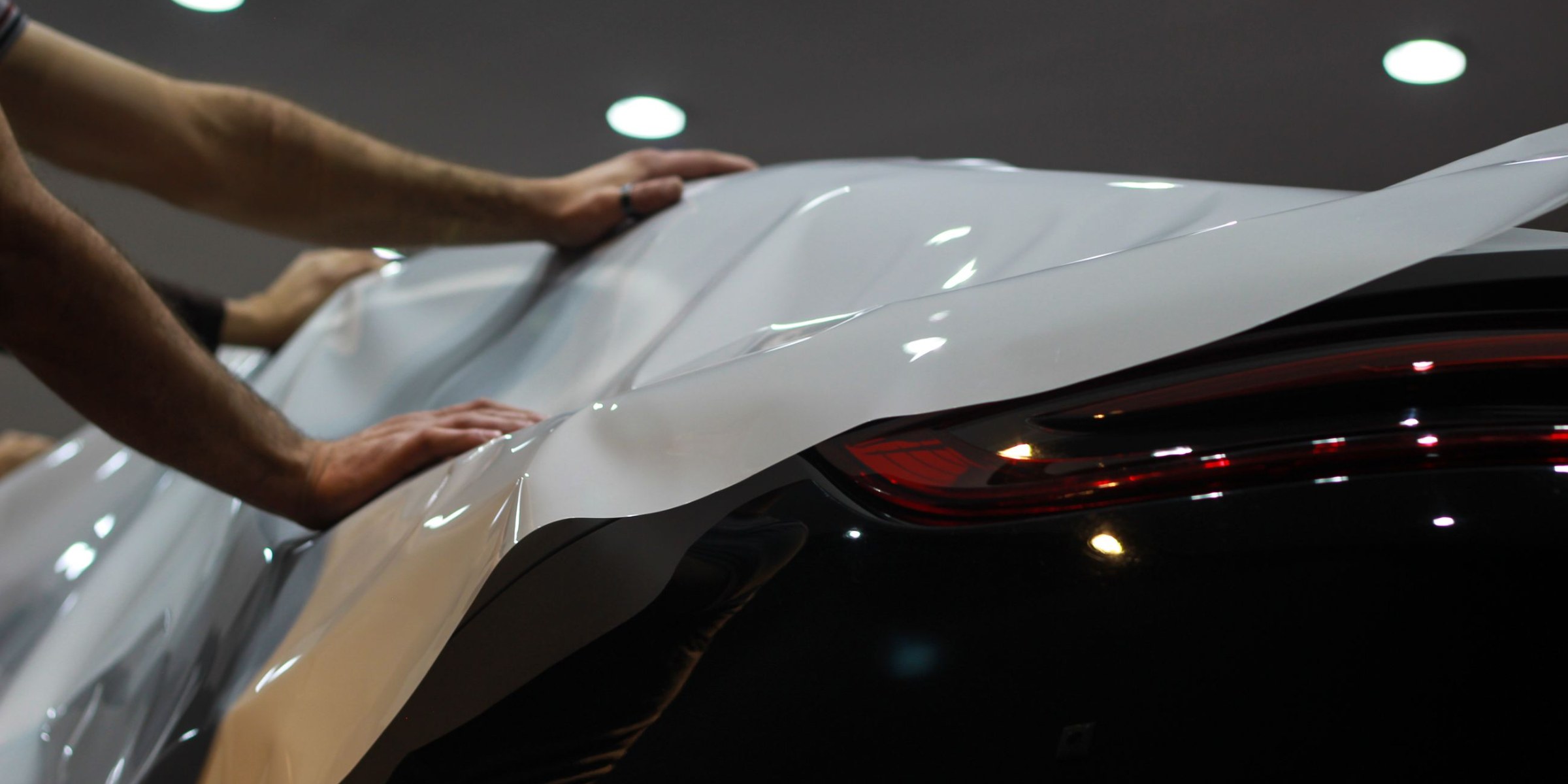 Clear paint protection film being laid over a dark rear quarter panel