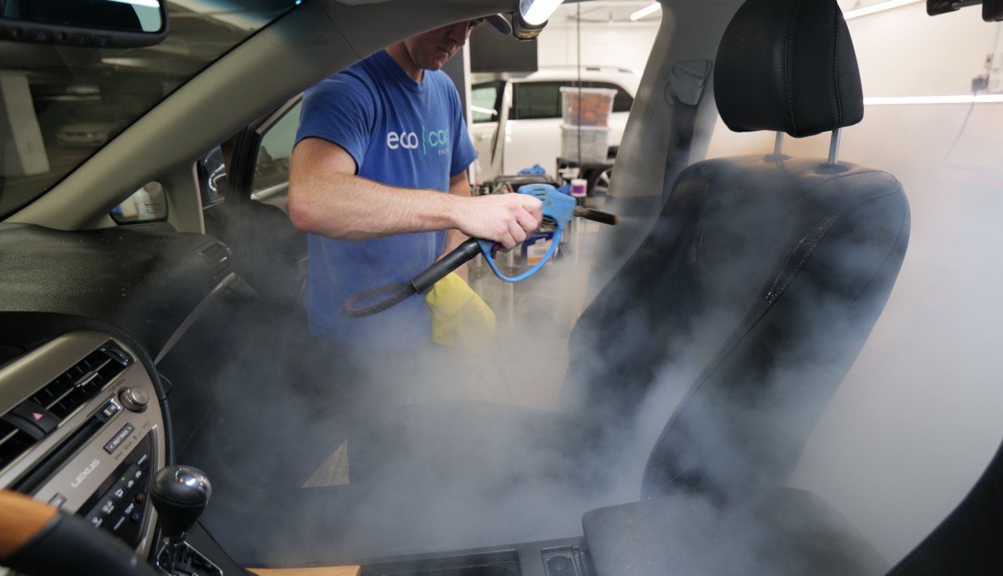 Eco Car Cafe technician steam cleaning a seat during an interior detail